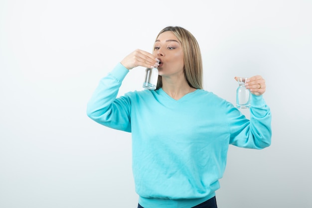 Foto retrato de mujer encantadora bebiendo agua de una jarra de vidrio