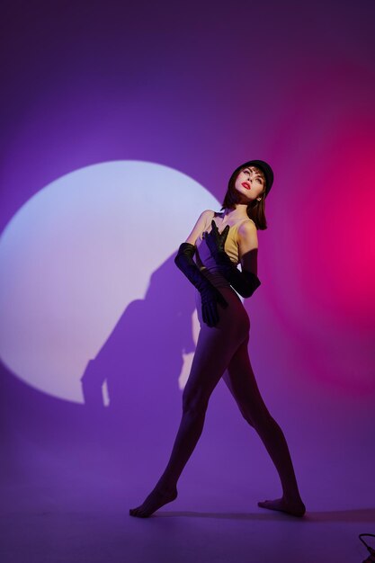 Retrato de una mujer encantadora en el centro de la escena posando con fondo púrpura de neón inalterado Foto de alta calidad