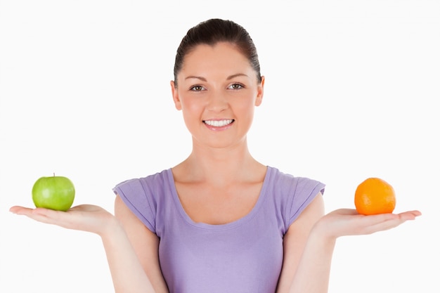 Retrato de una mujer encantadora con frutas mientras está parado