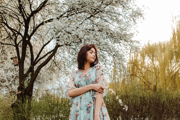 Retrato de mujer encantadora posando cerca de flores de cerezo de manzana flores florecientes en el jardín