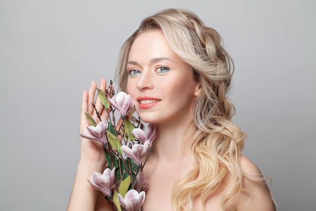 Retrato de una mujer encantadora y soñadora con piel estética natural perfecta y cabello saludable sobre un fondo de color gris