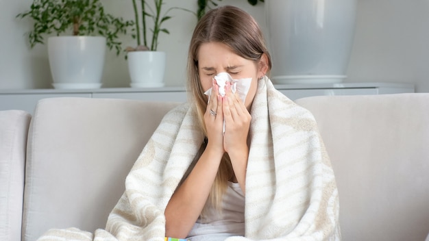 Retrato de mujer enferma con secreción nasal sonándose la nariz en un pañuelo de papel