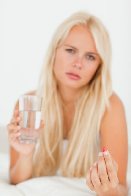 Retrato de una mujer enferma tomando una pastilla