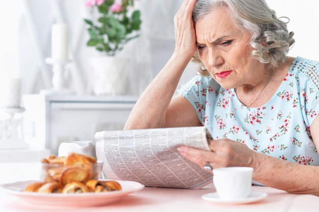 Retrato de mujer envejecida pensativa leyendo el periódico