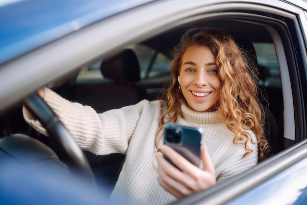 Retrato de una mujer enviando mensajes de texto en su teléfono inteligente mientras conduce un automóvil Aplicación de taxi del servicio de alquiler de vehículos compartidos