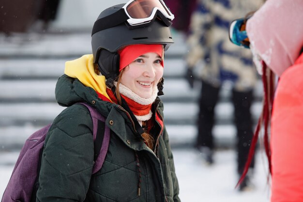 Retrato de una mujer esquiador, snowboarder en un casco, gafas y un gorro de punto