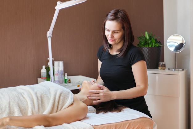 Retrato de mujer esteticista trabajando con paciente femenino en clínica de belleza