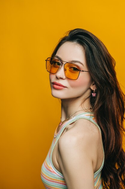 Retrato de mujer con estilo atractivo en gafas de sol con cabello largo morena