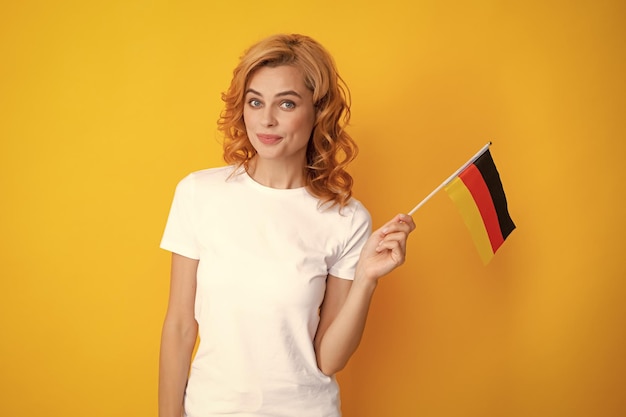 Retrato de mujer estudiante feliz sosteniendo la bandera alemana aislada sobre fondo amarillo Chica feliz sosteniendo la bandera de inmigración de Alemania y viajando en Europa Deutschland deutsche flag