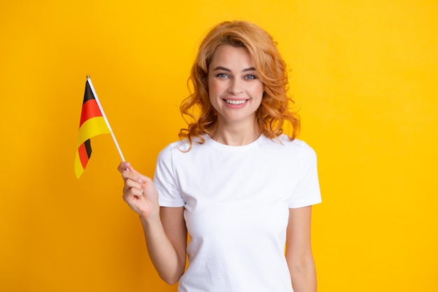 Retrato de mujer estudiante feliz sosteniendo la bandera alemana aislado sobre fondo amarillo