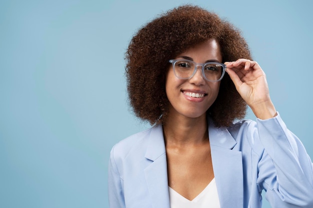 Retrato de mujer étnica positiva tocando sus nuevas gafas ópticas aislado fondo azul pastel