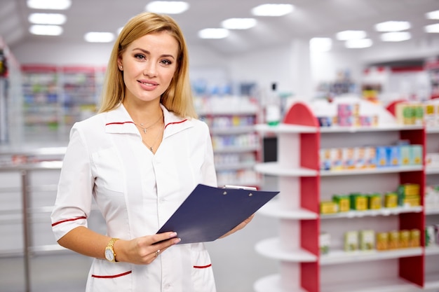 Retrato mujer farmacéutica escribiendo en el portapapeles en farmacia