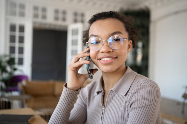 Retrato de una mujer feliz con anteojos trabajando en una oficina haciendo llamadas telefónicas a un cliente