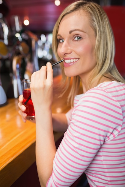 Retrato de mujer feliz con bebida sosteniendo paja