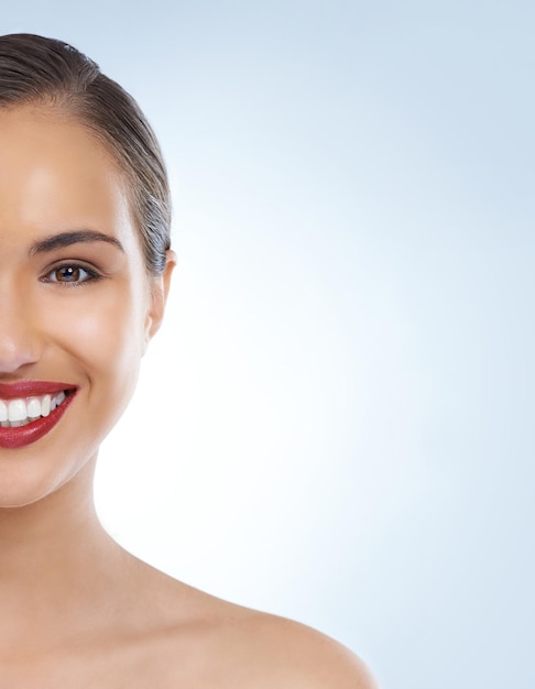 Retrato de mujer feliz y cara con lápiz labial rojo para maquillaje belleza o cosméticos en un fondo de estudio azul sonrisa de mujer joven o modelo para tratamiento facial en cosmetología en el espacio de maqueta