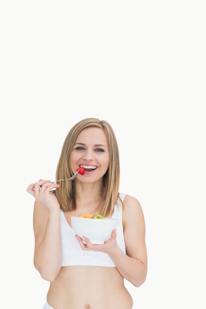 Retrato de mujer feliz comiendo de un plato de frutas