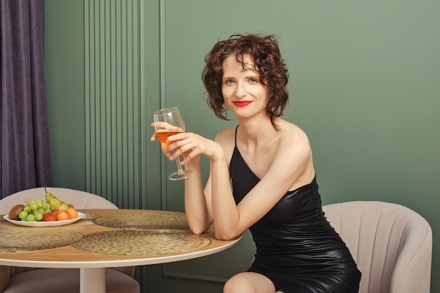 Retrato de una mujer feliz con una copa de vino en casa