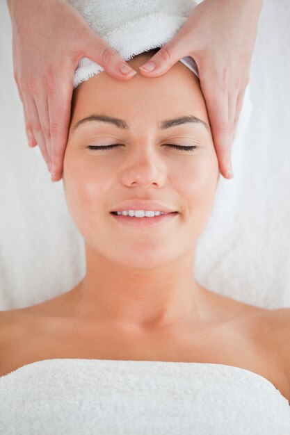 Foto retrato de una mujer feliz disfrutando de un masaje facial