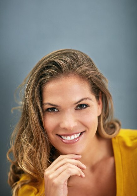 Retrato de mujer y feliz en el fondo en el estudio en confianza orgullo y sonrisa en fondo gris en Italia Persona femenina alegre y de primer plano como diseñadora gráfica en Milán para empresa o negocio
