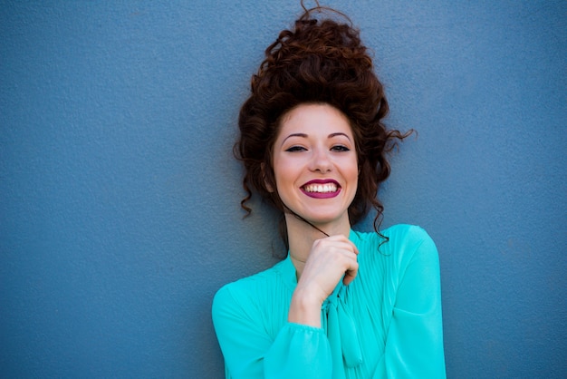 Retrato de una mujer feliz hermosa joven pelirroja en una pared azul