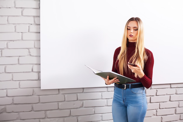 Retrato de mujer feliz joven empresaria cerca de pared blanca