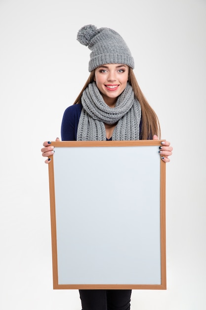 Retrato de una mujer feliz mostrando tablero en blanco aislado sobre un fondo blanco.