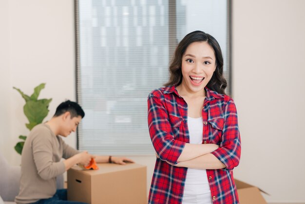 Retrato de mujer feliz durante la mudanza a casa llevando cajas de cartón