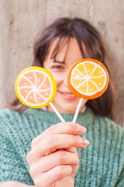 Retrato de mujer feliz muy joven posando con piruletas dulces.