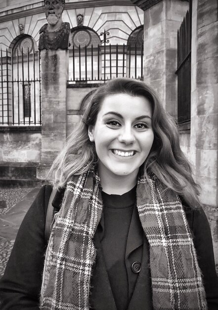 Foto retrato de una mujer feliz de pie contra un edificio