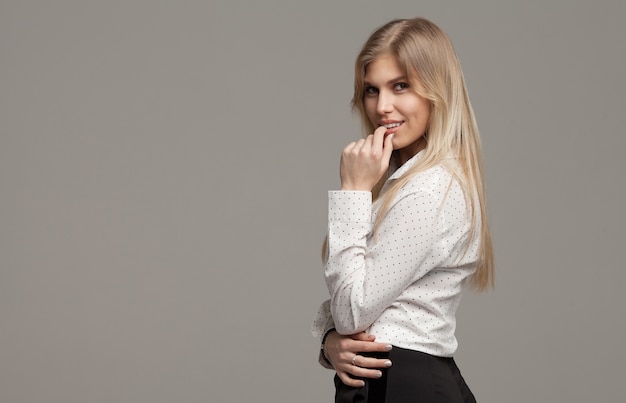 Retrato de una mujer feliz posando en gris