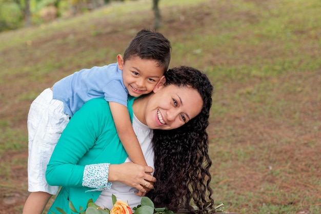 Retrato de una mujer feliz que lleva a su hijo sonriente en la espalda mientras juega