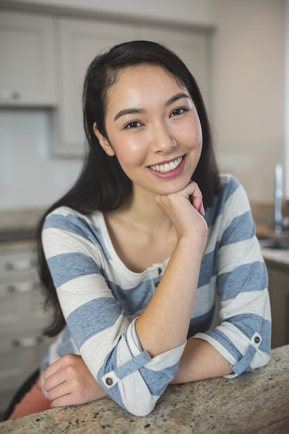 Retrato de mujer feliz sentada en la cocina