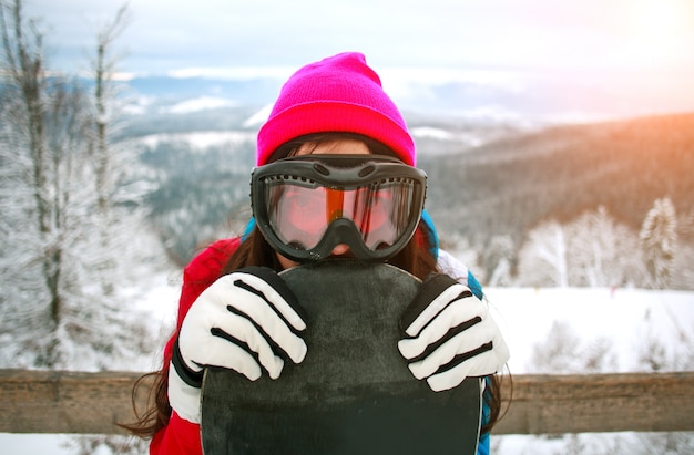 Retrato mujer feliz con snowboard en la cima de la montaña nevada