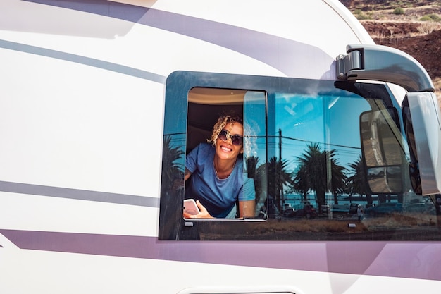 Retrato de mujer feliz sonriendo en la ventana de su moderna autocaravana Concepto de turista y viaje para vacaciones o estilo de vida de la vida de la furgoneta Jóvenes mujeres adultas felices en el destino