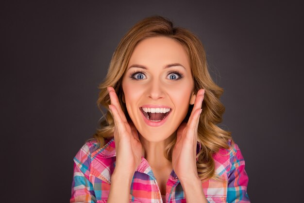 Retrato de mujer feliz sorprendida tocando su rostro con la boca abierta