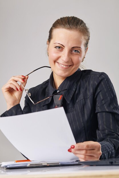 Retrato de una mujer feliz sosteniendo un papel en una mano y sus lentes en otra