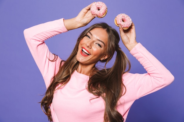 Retrato de una mujer feliz en sudadera posando con donas