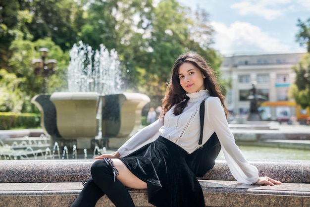 Retrato mujer feliz usar blusa blanca y falda negra cerca de la fuente pública