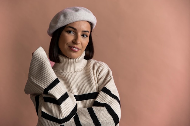 Retrato de una mujer feliz vestida con boina sonriendo y mirando a la cámara aislada sobre beige