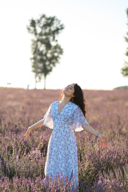 Retrato de una mujer feliz con un vestido azul disfrutando de un día soleado de verano en un campo de lavanda Aire fresco Estilo de vida