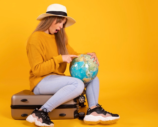 Retrato mujer feliz, viajero con un globo y una maleta, en espacio amarillo