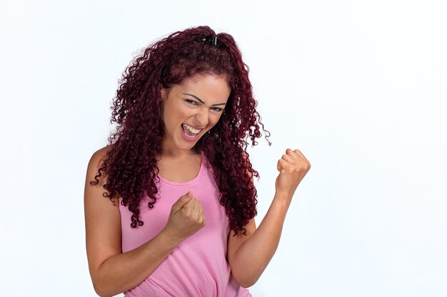 Foto retrato de una mujer feliz vibrando con éxito, puños cerrados