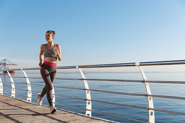 Retrato de mujer de fitness atractivo saludable corriendo cerca del mar.