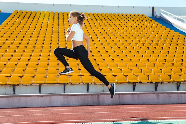 Retrato de una mujer fitness corriendo en el estadio