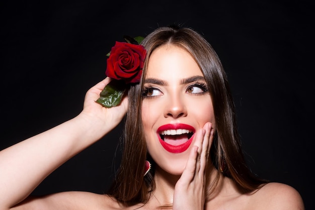 Retrato de una mujer con una flor de rosa Cara de mujer modelo de moda de belleza sobre un fondo negro Concepto de día de la mujer