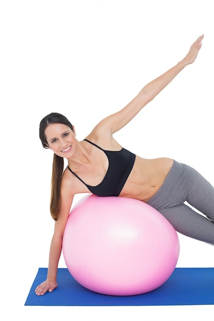 Retrato de una mujer en forma que se extiende en la bola de la aptitud