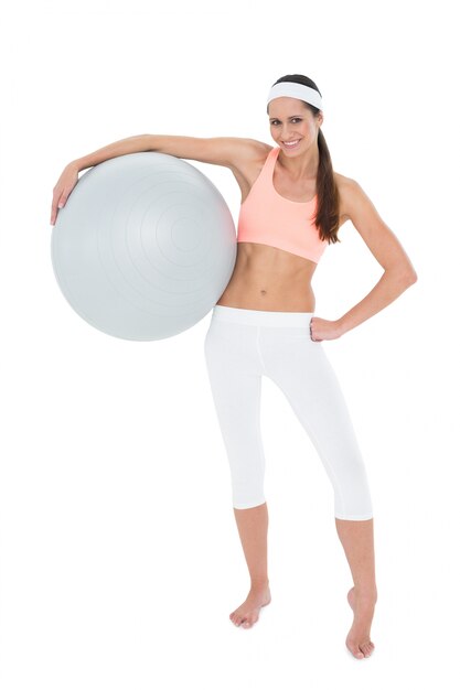 Foto retrato de una mujer en forma sonriente sosteniendo la bola de la aptitud