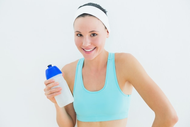 Retrato de una mujer en forma sonriente sosteniendo la botella de agua