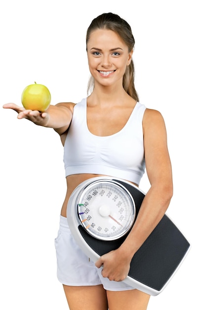 Retrato de una mujer en forma sosteniendo una báscula y sosteniendo una manzana