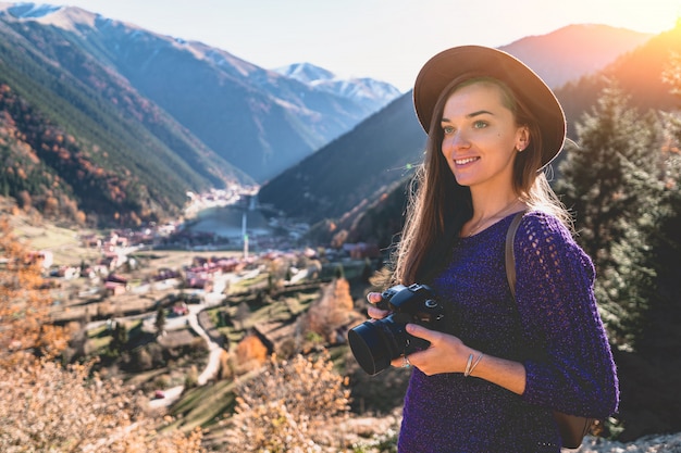 Foto retrato de mujer fotógrafa de moda con estilo inconformista viajero en un sombrero de fieltro durante la toma de fotografías de las montañas y el lago uzungol en trabzon durante el viaje a turquía